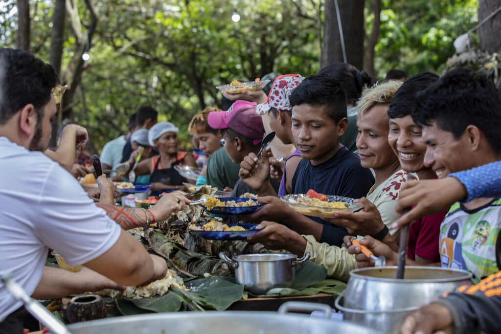 Projeto Gosto da Amazônia leva chefs de cozinha do Rio de Janeiro até a Terra Indígena Paumari, no sul do Amazonas, para conhecer o manejo do pirarucu e seus impactos econômicos, sociais e ambientais na região. Os chefs criarão pratos com o pirarucu, o maior peixe de escamas de água doce do mundo, para contribuir com a introdução do produto no mercado do Rio de Janeiro.
Na foto, jovens Paumari servem-se do almoço preparado pelas cozinheiras e cozinheiros do Rio de Janeiro.
Foto Marizilda Cruppe/Divulgação